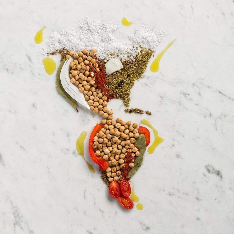 Load image into Gallery viewer, A map of North, Central, and South America covered with garbanzo beans, herbs, spices, peppers, tomato, and onion. 
