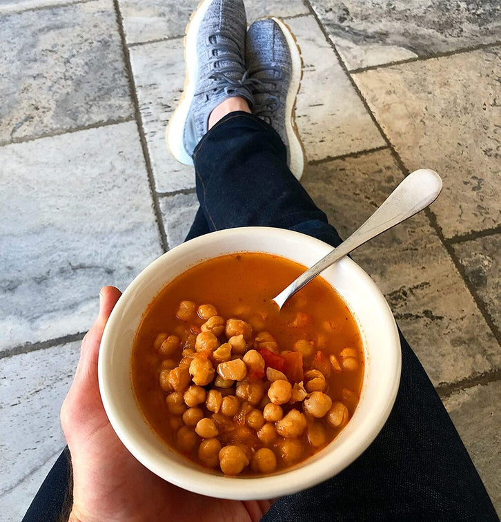 Load image into Gallery viewer, A person enjoys a bowl of Panamanian Garbanzo Sofrito.
